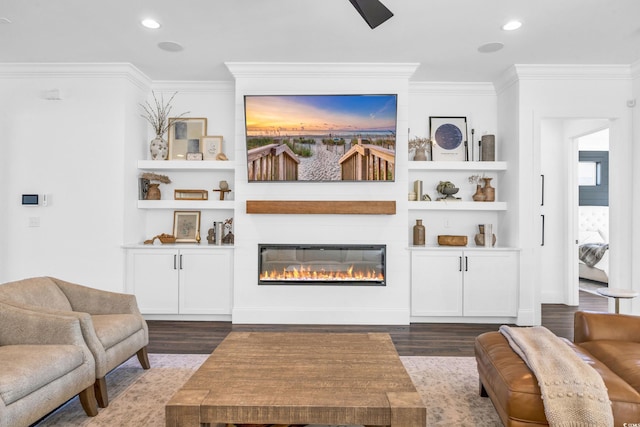 living room featuring built in shelves, dark wood-type flooring, and ornamental molding