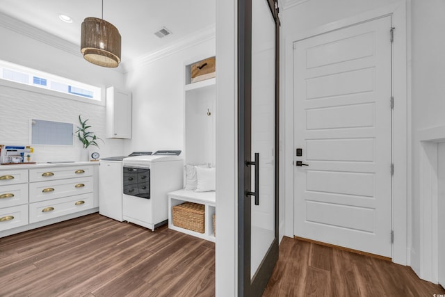 washroom featuring crown molding, cabinets, dark hardwood / wood-style floors, and washing machine and clothes dryer