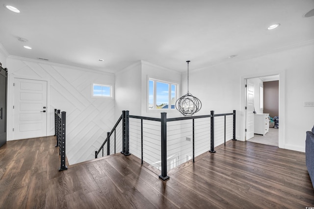 hall featuring a barn door, ornamental molding, dark hardwood / wood-style floors, and a chandelier