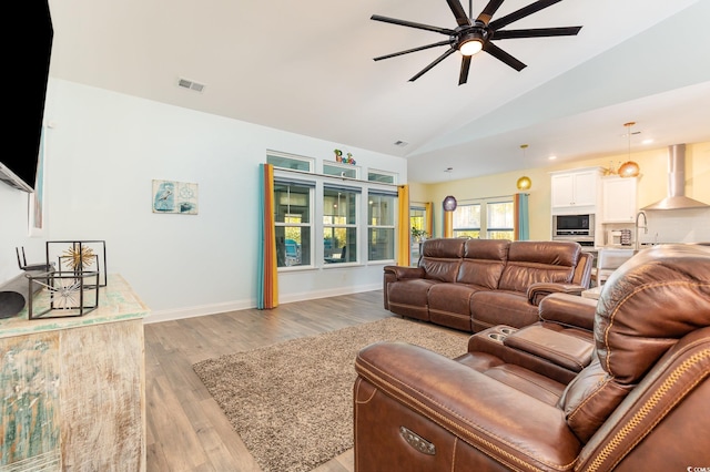 living room featuring ceiling fan, sink, high vaulted ceiling, and light wood-type flooring