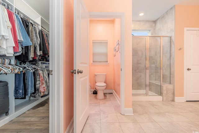 bathroom featuring tile patterned flooring, toilet, and walk in shower