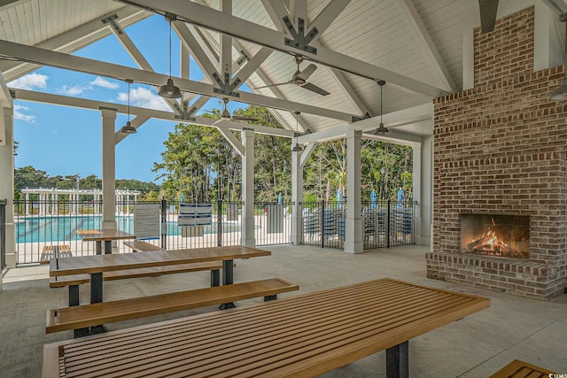 view of patio / terrace with an outdoor brick fireplace, a community pool, and ceiling fan