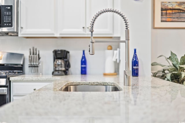 kitchen with appliances with stainless steel finishes, white cabinets, decorative backsplash, and light stone countertops