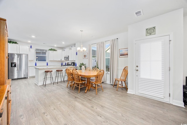 dining space with a notable chandelier, light wood finished floors, recessed lighting, visible vents, and baseboards