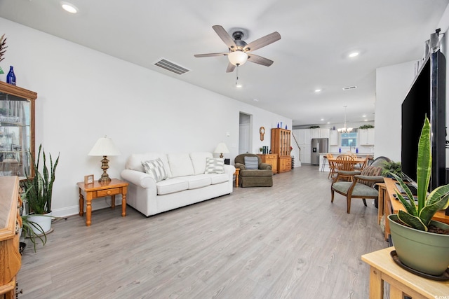 living room featuring ceiling fan with notable chandelier, light wood-type flooring, visible vents, and recessed lighting