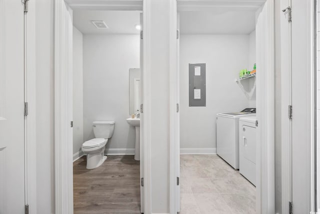 bathroom with toilet, visible vents, baseboards, electric panel, and washer and clothes dryer