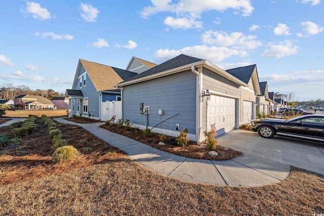 view of side of property featuring driveway, an attached garage, and a residential view