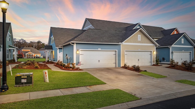 view of front of house featuring a garage, concrete driveway, a shingled roof, and a lawn