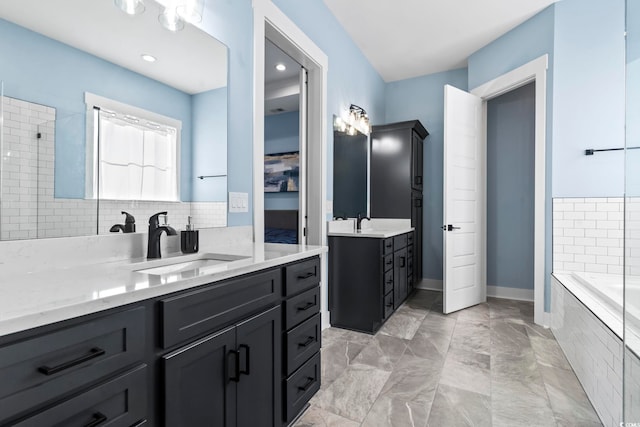 bathroom with vanity, tasteful backsplash, and tiled bath