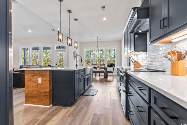 kitchen featuring sink, backsplash, light hardwood / wood-style floors, decorative light fixtures, and stainless steel electric stove