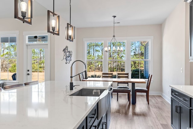 kitchen with decorative light fixtures, sink, hardwood / wood-style flooring, light stone countertops, and an inviting chandelier