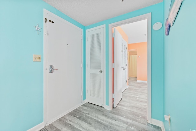 hall with a textured ceiling and light wood-type flooring