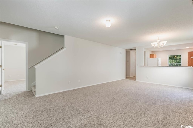 unfurnished living room featuring carpet and a notable chandelier