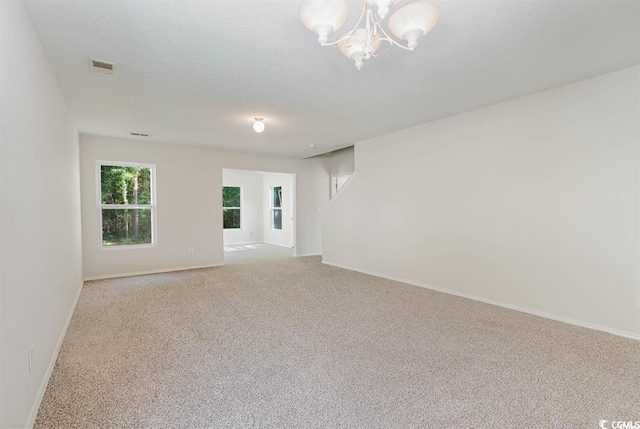 empty room with an inviting chandelier and light carpet