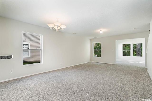 unfurnished room with an inviting chandelier and carpet floors