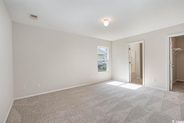 unfurnished bedroom featuring a walk in closet, connected bathroom, a closet, and carpet