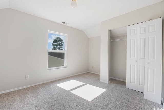 unfurnished bedroom featuring a closet, lofted ceiling, and light carpet