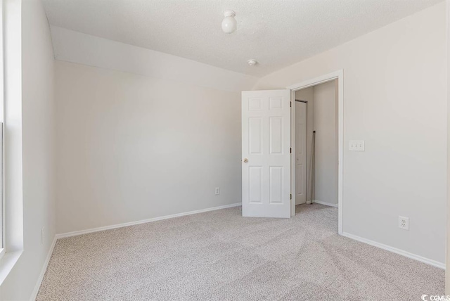 spare room with light carpet and a textured ceiling