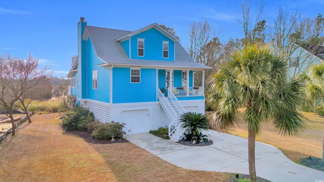 beach home featuring a garage, a front yard, and covered porch