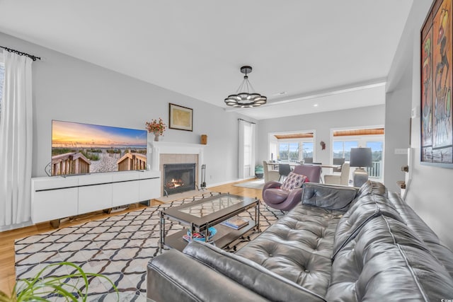 living room with a tiled fireplace, an inviting chandelier, and hardwood / wood-style floors