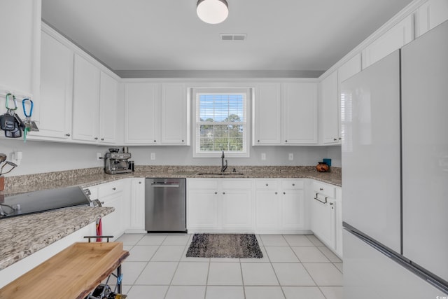 kitchen featuring white cabinetry, white refrigerator, sink, stainless steel dishwasher, and light tile patterned floors