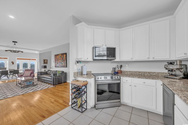 kitchen featuring appliances with stainless steel finishes, white cabinets, light stone countertops, and light hardwood / wood-style flooring