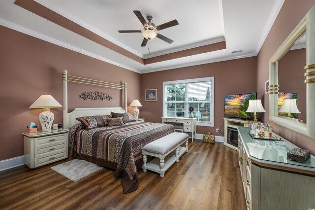 bedroom featuring wood-type flooring, ornamental molding, ensuite bathroom, and a tray ceiling