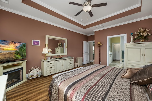 bedroom with hardwood / wood-style floors, ornamental molding, a raised ceiling, and ensuite bathroom