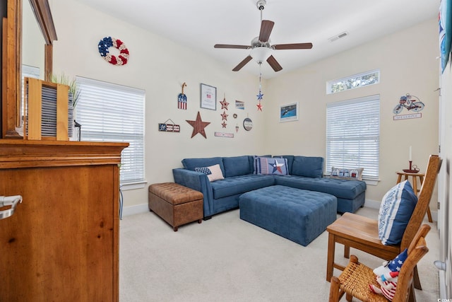 living area with light carpet, ceiling fan, visible vents, and baseboards