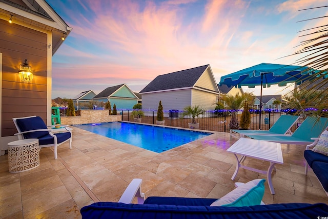 pool at dusk featuring a patio area, fence, and a fenced in pool