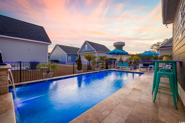 pool at dusk featuring a fenced in pool, a patio, and fence