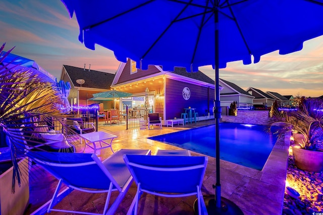 pool at dusk featuring a patio area and a swimming pool