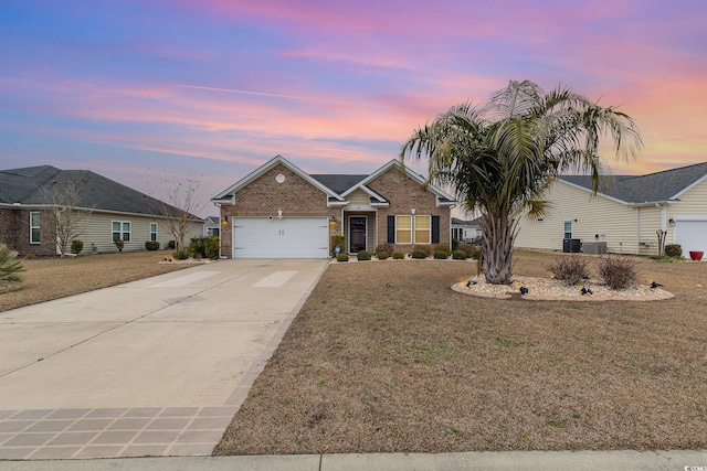 ranch-style house with central AC unit, concrete driveway, a garage, a lawn, and brick siding