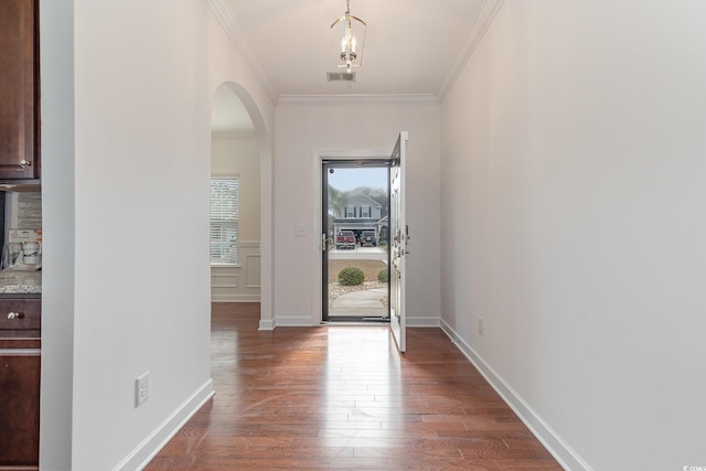 entryway featuring dark wood-style floors, baseboards, visible vents, arched walkways, and ornamental molding