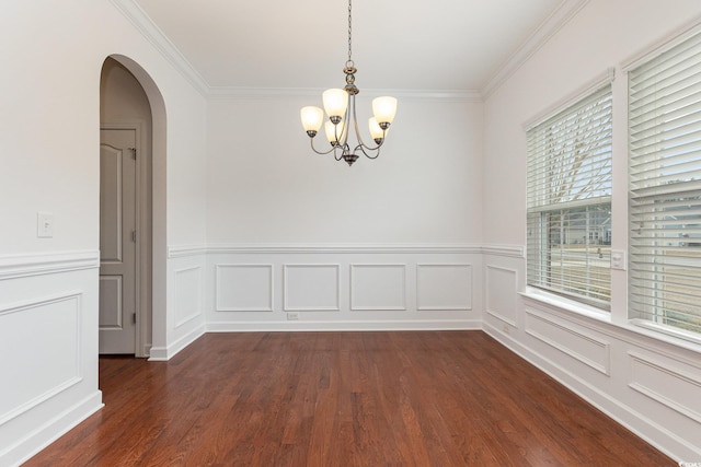 unfurnished room featuring arched walkways, crown molding, dark wood-type flooring, and an inviting chandelier