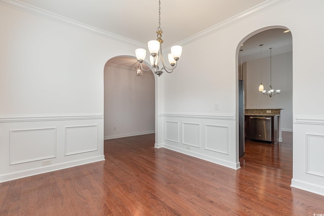 unfurnished dining area with arched walkways, crown molding, an inviting chandelier, and wood finished floors