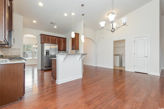 kitchen featuring a breakfast bar, stainless steel appliances, arched walkways, an inviting chandelier, and decorative backsplash