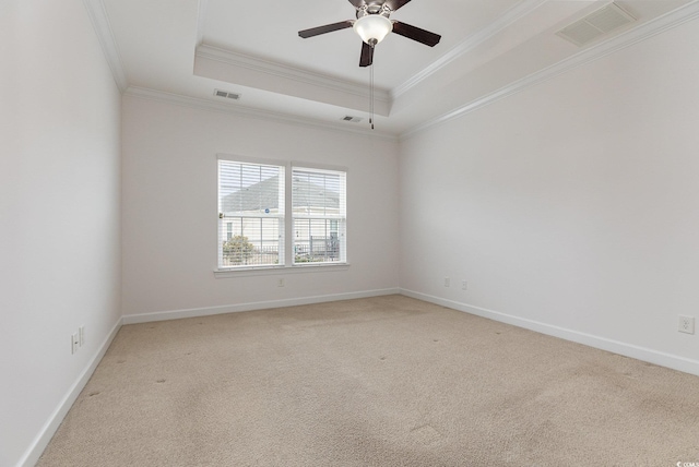 unfurnished room featuring visible vents, light colored carpet, a tray ceiling, and ornamental molding