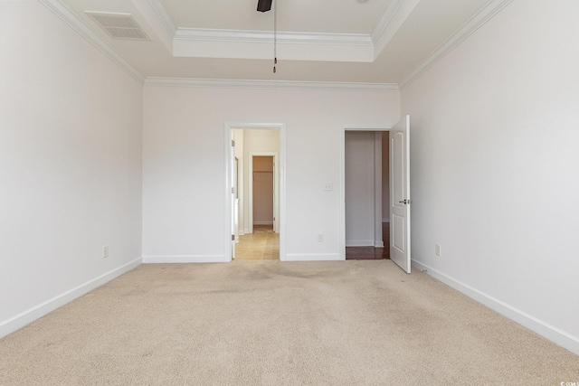 unfurnished bedroom with a tray ceiling, ornamental molding, visible vents, and light carpet