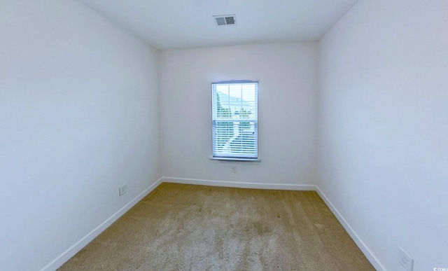 unfurnished room featuring carpet, visible vents, and baseboards