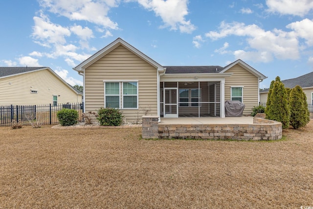 rear view of property featuring a patio, fence, a lawn, and a sunroom