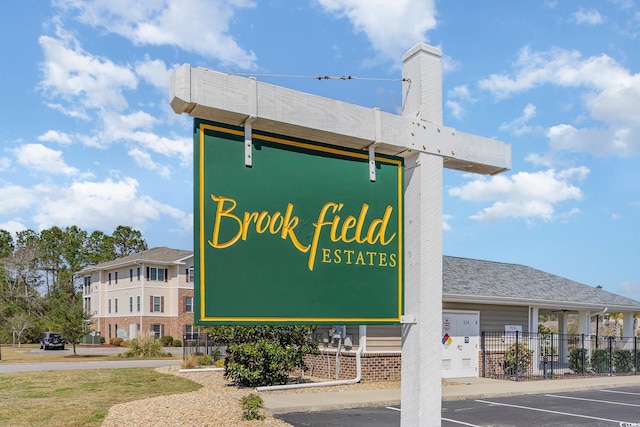 community sign featuring uncovered parking and fence