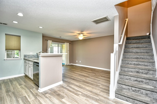 kitchen with recessed lighting, light wood-style floors, dishwasher, a peninsula, and a textured ceiling