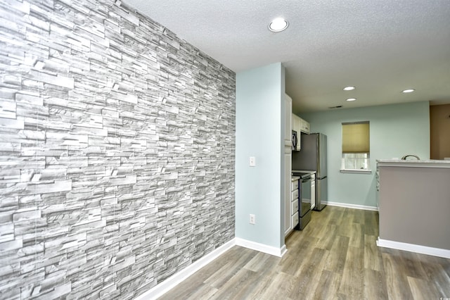 corridor featuring wood finished floors, recessed lighting, a textured ceiling, and baseboards