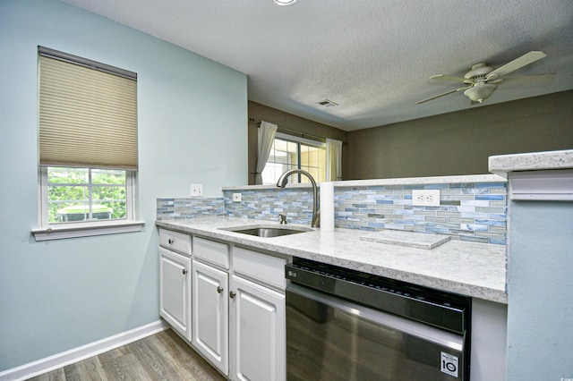 kitchen featuring dishwashing machine, a sink, decorative backsplash, wood finished floors, and a textured ceiling