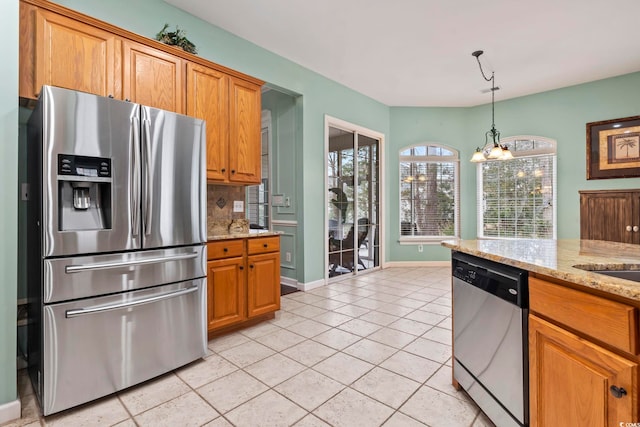 kitchen featuring appliances with stainless steel finishes, hanging light fixtures, tasteful backsplash, light stone countertops, and a chandelier