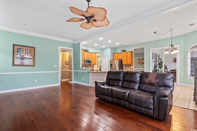 living room featuring crown molding, dark hardwood / wood-style floors, and ceiling fan with notable chandelier