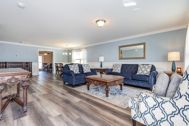 living room with crown molding, ceiling fan with notable chandelier, and hardwood / wood-style floors