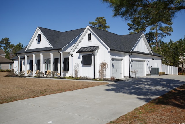 modern farmhouse with central AC unit, covered porch, a garage, concrete driveway, and a front lawn