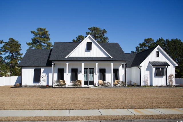 modern farmhouse featuring board and batten siding, a porch, roof with shingles, and fence